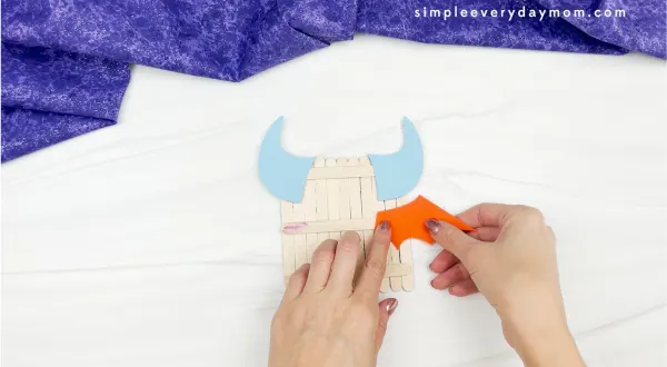 hands gluing wings to popsicle stick monster craft
