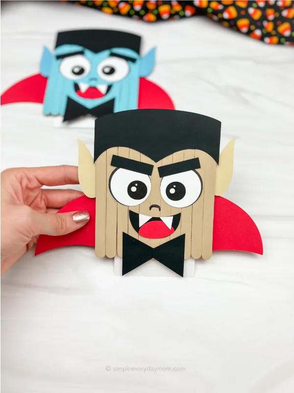 hand holding vampire popsicle stick craft with another one in the background