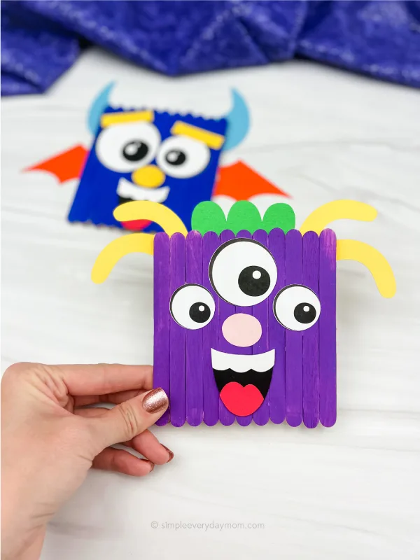 hand holding monster popsicle stick craft with a 2nd one in the background