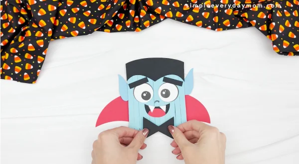 hands gluing bowtie to popsicle stick vampire craft