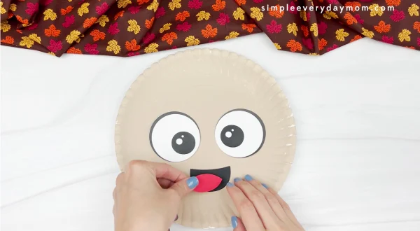hands gluing tongue to paper plate pilgrim craft