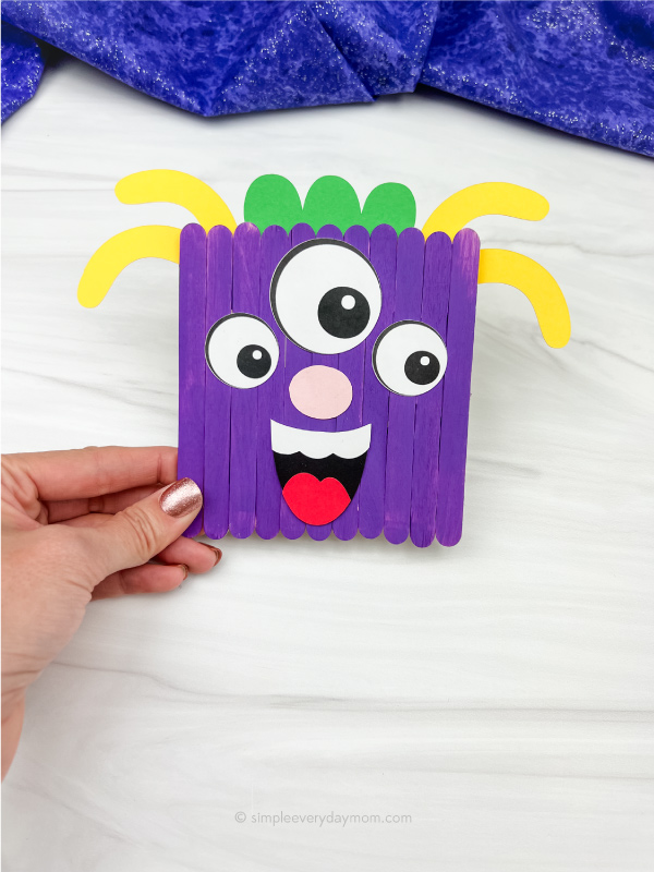 hand holding monster popsicle stick craft