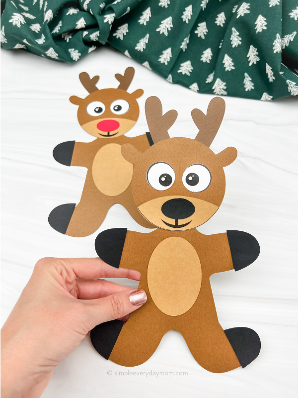 hand holding reindeer gingerbread man in disguise craft with a 2nd one in the background