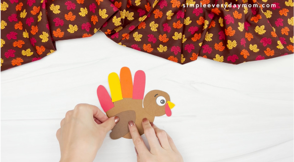 hand gluing wing to handprint turkey card craft