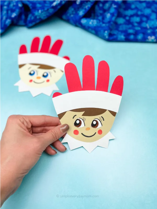 hand holding elf on the shelf craft with another one in the background