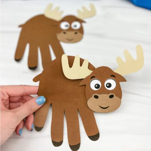 hand holding moose handprint craft with a second one in the background