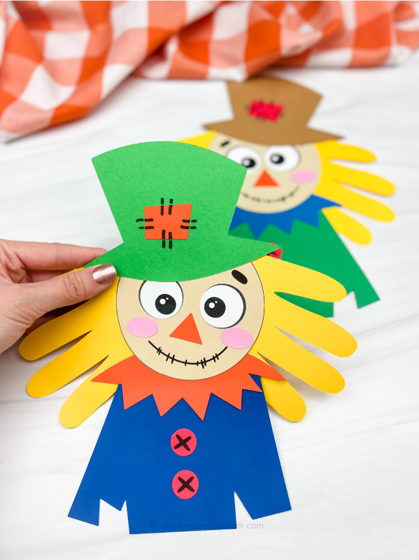 hand holding handprint scarecrow craft with another one in the background