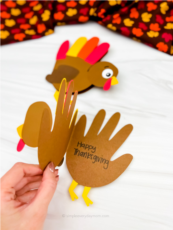hand opening handprint turkey card craft with a 2nd craft in the background