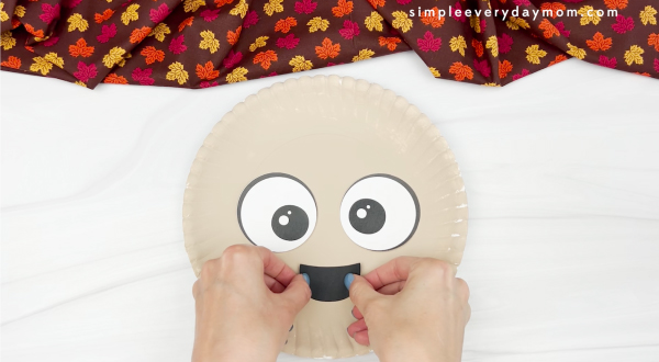 hands gluing mouth to paper plate pilgrim craft