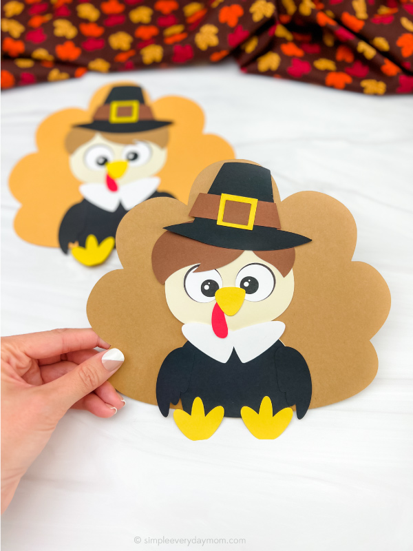 hand holding pilgrim disguise a turkey craft with a second one in the background