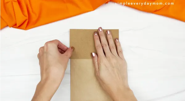 hand gluing brown paper to paper bag acorn craft