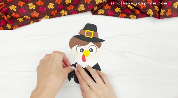 hands gluing wing to disguise a turkey craft