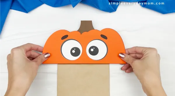 hand gluing top of pumpkin to paper bag pumpkin craft
