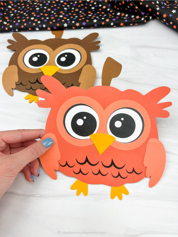 hand holding owl pumpkin craft with another one in the background
