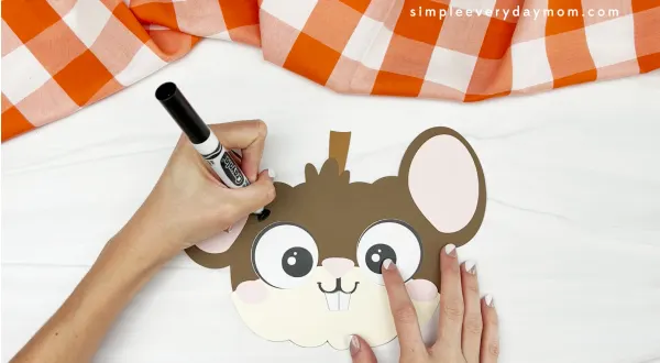 hands drawing eyebrows on mouse pumpkin craft