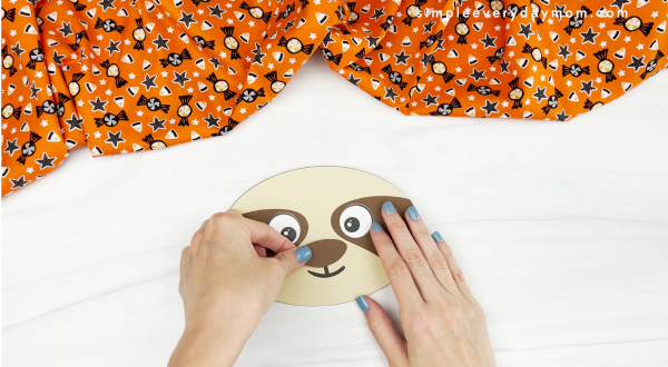 hands gluing nose to sloth pumpkin craft