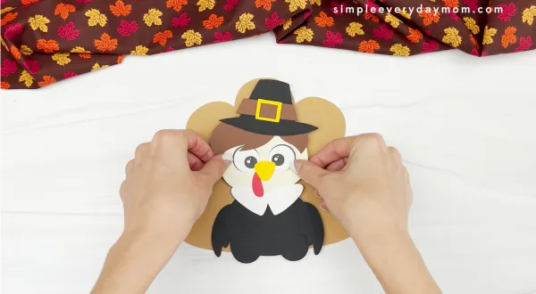 hands gluing feathers to disguise a turkey craft