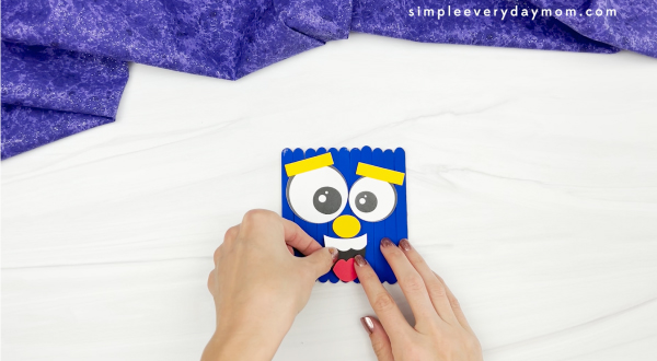 hands gluing mouth to popsicle stick monster craft