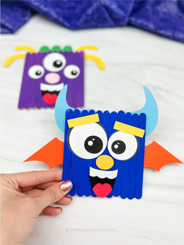 hand holding monster popsicle stick craft with a 2nd one in the background