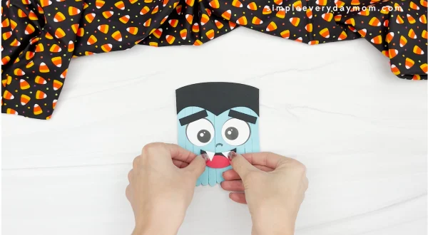 hands gluing mouth to popsicle stick vampire craft