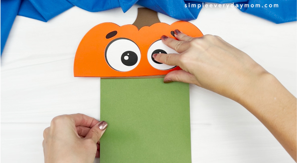 hand gluing green background to paper bag pumpkin craft