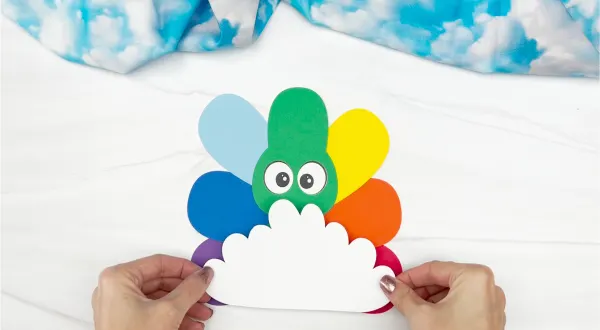 hands gluing cloud to rainbow disguise a turkey craft