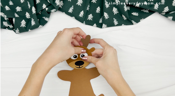 hands gluing antler to reindeer gingerbread man disguise craft