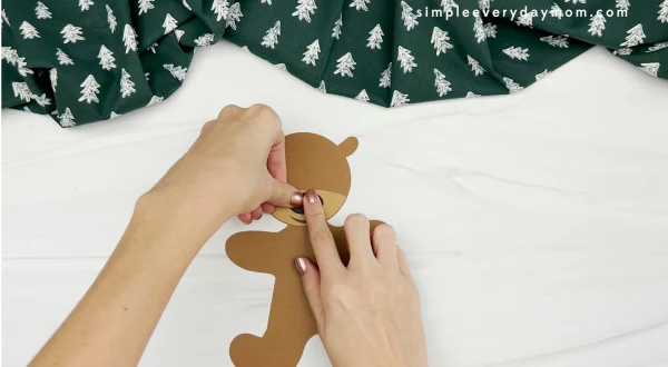 hands gluing nose to reindeer gingerbread man disguise craft
