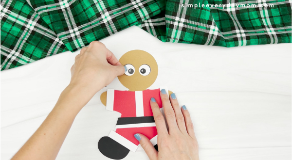 hands gluing eye to Santa gingerbread man disguise craft