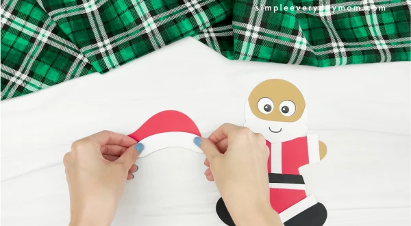 hands gluing fluff to hat of Santa gingerbread man disguise craft