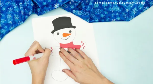hand drawing icing decoration onto snowman gingerbread man disguise craft