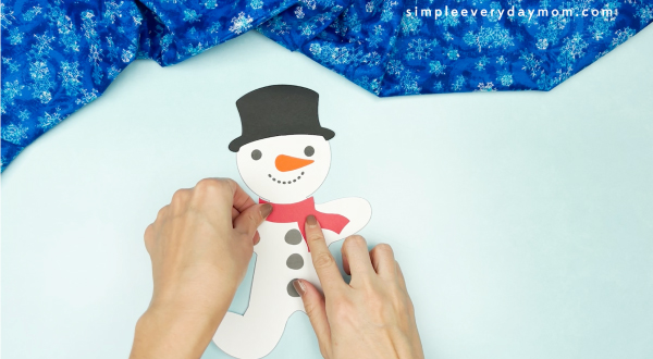 hand gluing scarf onto snowman gingerbread man disguise craft