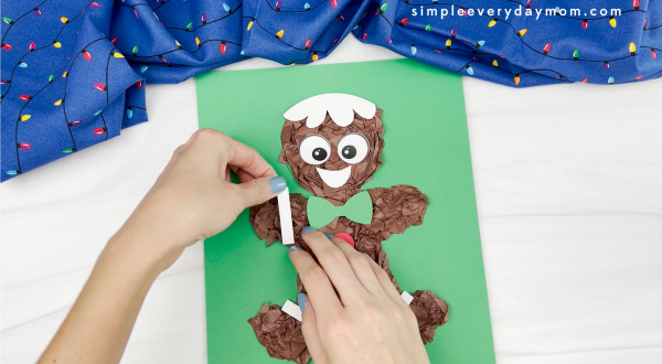 hands gluing icing paper decoration to tissue paper gingerbread man craft