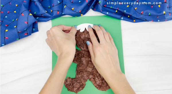 hands gluing icing. hair decoration to tissue paper gingerbread man craft