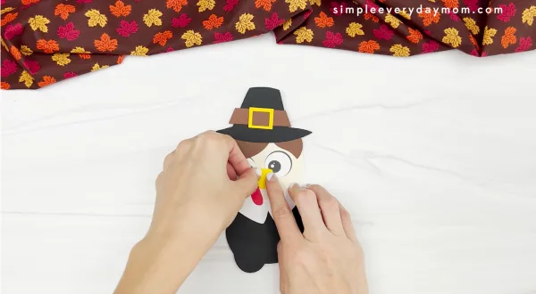 hands gluing beak to disguise a turkey craft