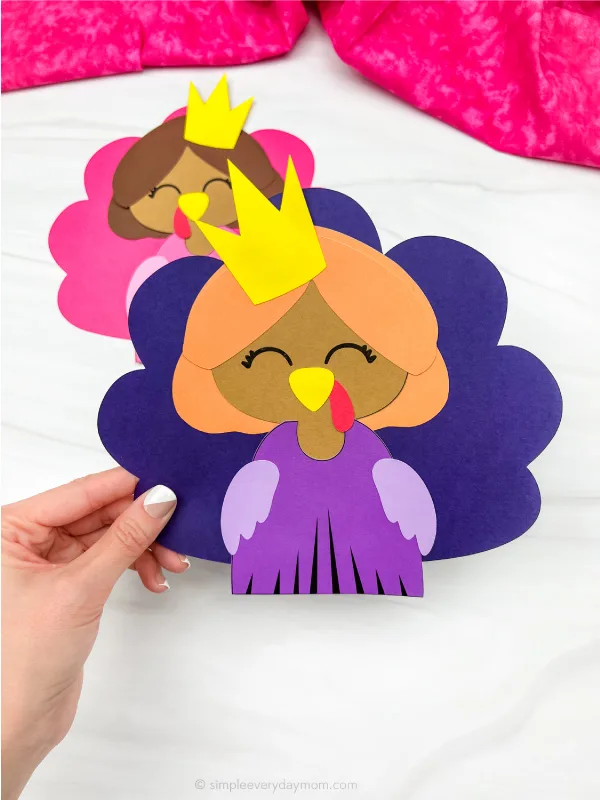 hand holding princess turkey disguise craft with a second one in the background