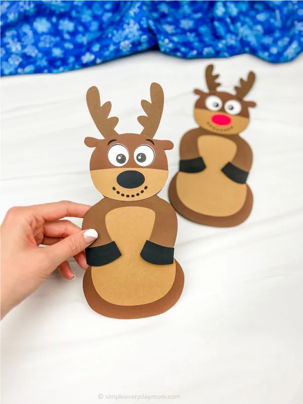hand holding reindeer disguised as a snowman craft with another one in the background