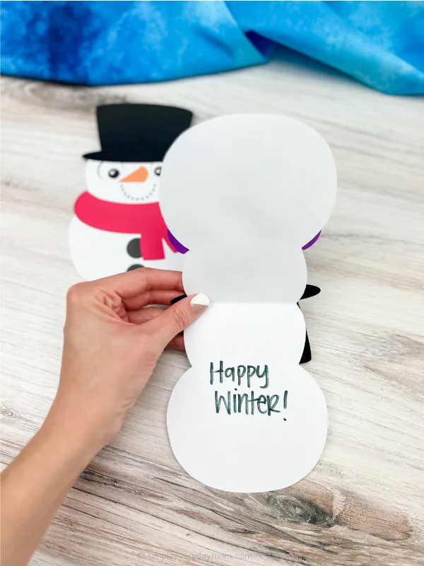 hands opening snowman card craft with a 2nd one in the background