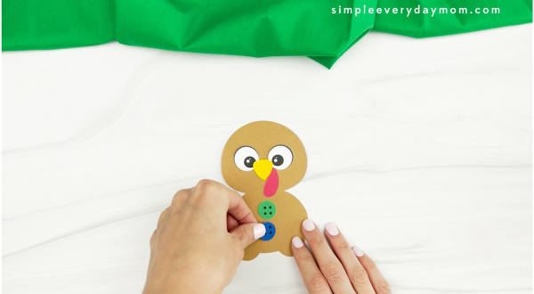 hands gluing buttons to gingerbread turkey disguise craft