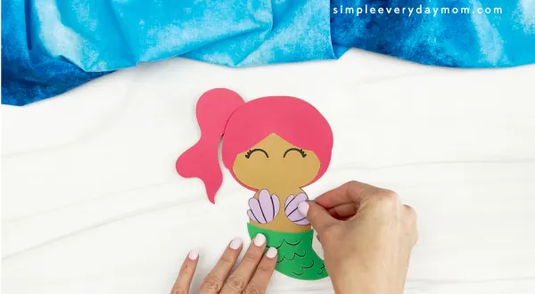 hands gluing seashell top to mermaid turkey disguise craft