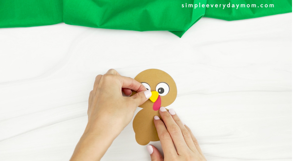 hands gluing beak to gingerbread turkey disguise craft