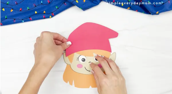 hands gluing hat to elf card craft