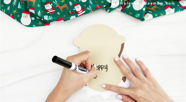 hands writing a note on the inside of elf card craft