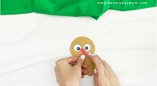 hands gluing snood to gingerbread turkey disguise craft