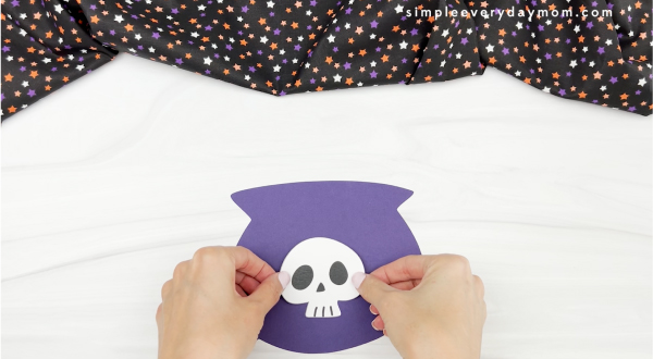 hands gluing skull to witches brew handprint craft