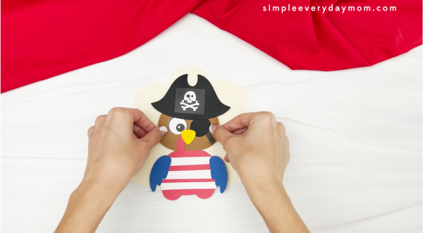 hands gluing feathers to pirate turkey disguise craft