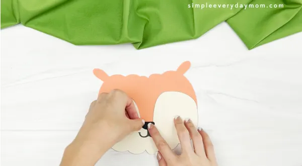 hands gluing nose to squirrel pumpkin craft