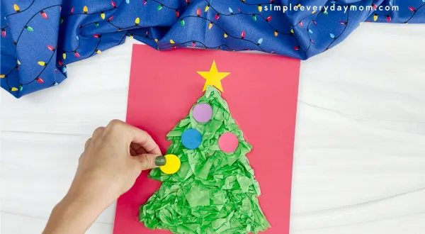 hands assembling ornaments onto Christmas tree tissue paper craft