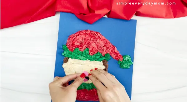 hand is placing paper nose on elf tissue paper craft