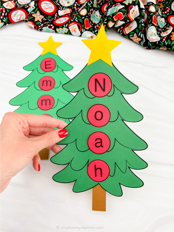 hand holding Christmas tree name craft with a second one in the background